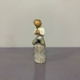 Small figurine of a kneeling child holding a flower