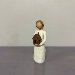 Small figurine of a person holding a tiny house