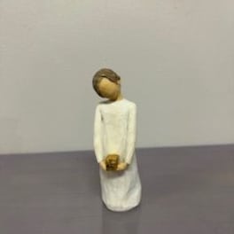 Small figurine of a person in a white dress holding a tiny object