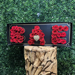 Red roses arranged to spell BAE on a black sign