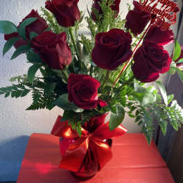 Bouquet of red roses in a glass vase with a Valentine sign