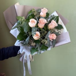Bouquet of pale pink roses wrapped in white and taupe paper