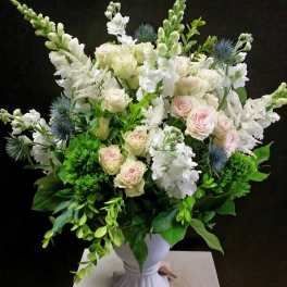 White and blush bouquet in a white pedestal vase