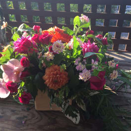 Mixed bouquet with pink and orange flowers in a low container