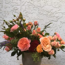 Peach and pink roses arranged in a gray vase