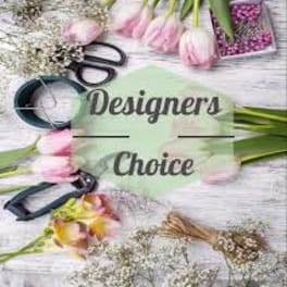 Pink tulips and floral tools arranged around a Designers Choice label on a wood surface