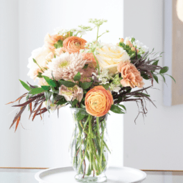 Peach and white flowers arranged in a clear glass vase