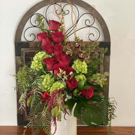 Tall arrangement of red roses and green hydrangeas in a white vase