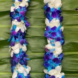 Purple, blue, and white flower lei on a green leaf background