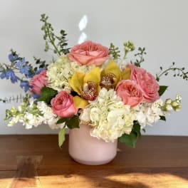 Pink roses and white hydrangeas in a blush vase with yellow orchids