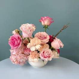 Pink roses and carnations arranged in a white bowl vase