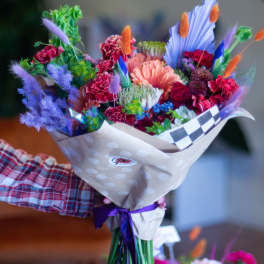 Colorful bouquet with pink, purple, and orange flowers wrapped in paper