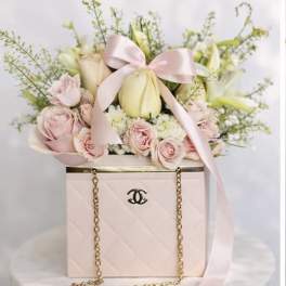 Pink and white flowers arranged in a pale pink box with a ribbon bow