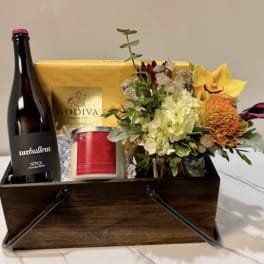 Gift basket with flowers, wine, chocolates, and a candle