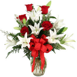 Red roses and white lilies in a glass vase with a red bow
