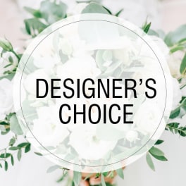 White floral arrangement with green foliage and a "Designer’s Choice" label