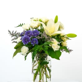 White lilies and purple daisies in a glass jar vase