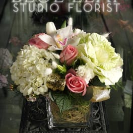 Pink roses and white orchids arranged in a glass vase