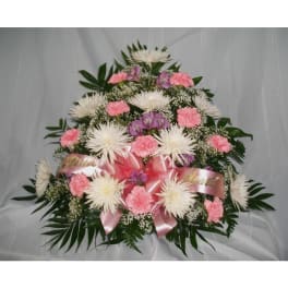 Pink and white floral spray with ribbon on a white draped background