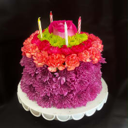 Tiered floral cake with a pink rose topper and striped candles