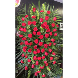 Tall standing spray of red roses and carnations with lush greenery