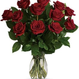 Dozen red roses arranged in a clear glass vase