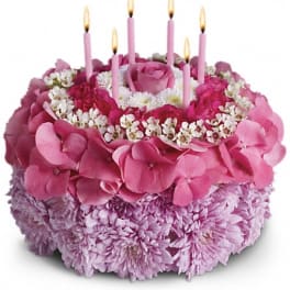 Pink floral cake with lit candles on top