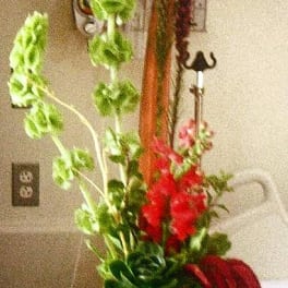 Tall arrangement with red and purple flowers in a black vase