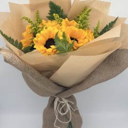 Bouquet of yellow sunflowers wrapped in brown paper and burlap