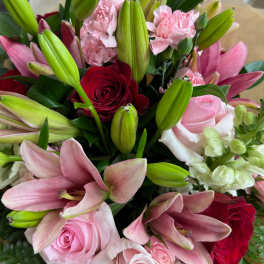 Bouquet of pink lilies, roses, and carnations with a red rose accent