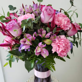 Pink roses and carnations in a purple glass vase
