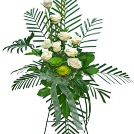 Standing floral spray with white roses and palm fronds on a tripod easel