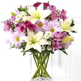 Bouquet of white lilies and pink daisies in a clear glass vase