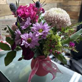 Pink and lavender mixed bouquet in a pink vase with ribbon