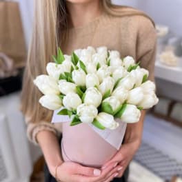 Woman holding a bouquet of white tulips in a pink wrap