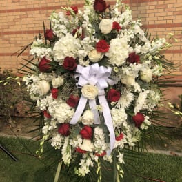 Large standing floral spray with red and white roses and a white ribbon bow