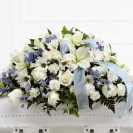 White and blue funeral spray with lilies, roses, and daisies