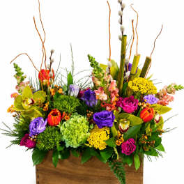 Colorful mixed flower arrangement in a wooden box with tall branches