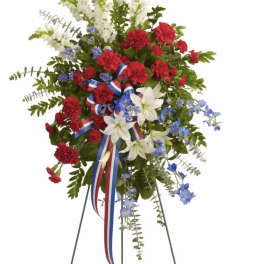 Standing floral spray with red, white, and blue flowers on a metal easel