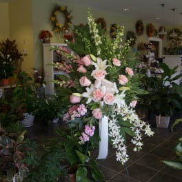 Tall floral standing spray with pink roses, white lilies, and cascading white orchids