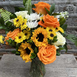 Orange roses and yellow sunflowers in a glass vase