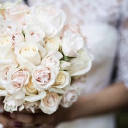 Bride holding a bouquet of white and blush roses
