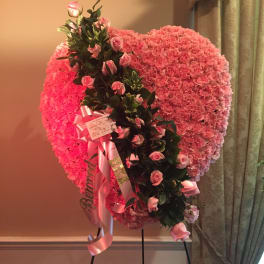 Pink heart-shaped floral standing arrangement with roses and ribbons