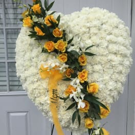 Heart-shaped white floral spray with yellow roses and ribbon