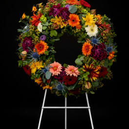Colorful floral wreath on a white easel against a black background