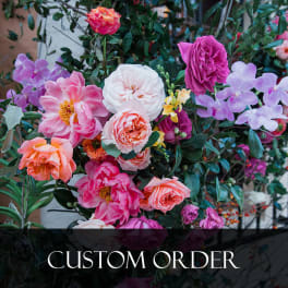 Mixed bouquet of pink, purple, and white flowers with dense greenery