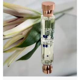 Perfume bottle beside a white flower and green leaves
