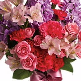 Bouquet of pink, purple, and red flowers tied with a satin ribbon