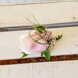 Small pink and white boutonniere with tiny blossoms and greenery