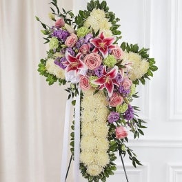 Standing floral cross with pink roses and lilies on an easel
